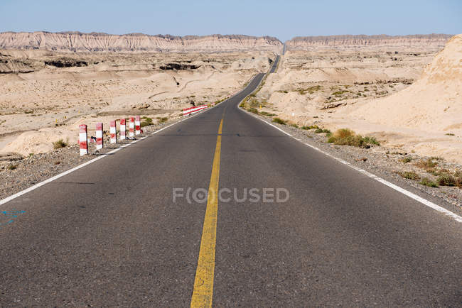 Asphaltstraße in der Wüste mit malerischen felsigen Bergen bei sonnigem Wetter — Stockfoto
