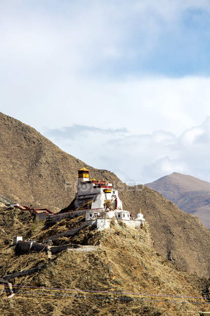 Vista de ángulo bajo de la pasarela peatonal y el edificio en la montaña rocosa en el Tíbet - foto de stock
