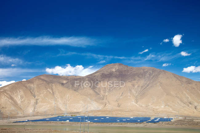 Hermoso paisaje con montañas y paneles solares en el día soleado - foto de stock