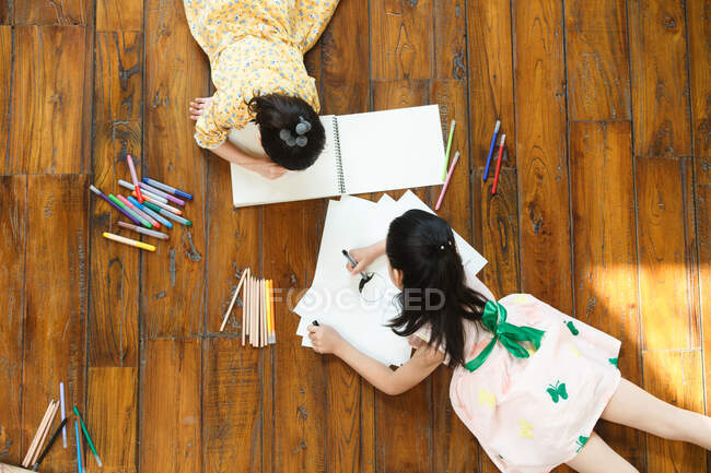 Two girls lying on floor drawing — Stock Photo