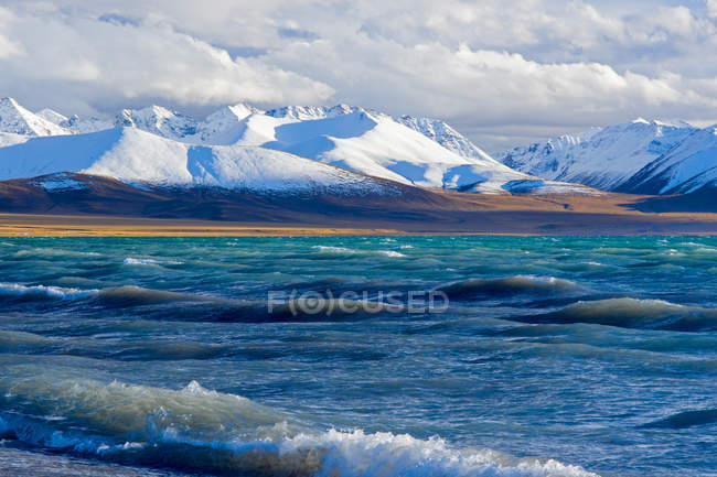 Красивое волнистое озеро и заснеженные горы в Тибете — стоковое фото