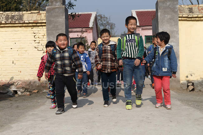 Felici alunni rurali cinesi che tornano a casa da scuola — Foto stock