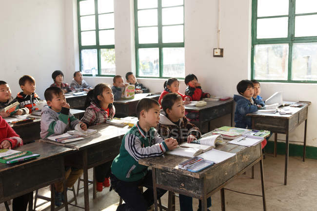 Focused Chinese school students sitting at desks and studying in rural primary school — Stock Photo