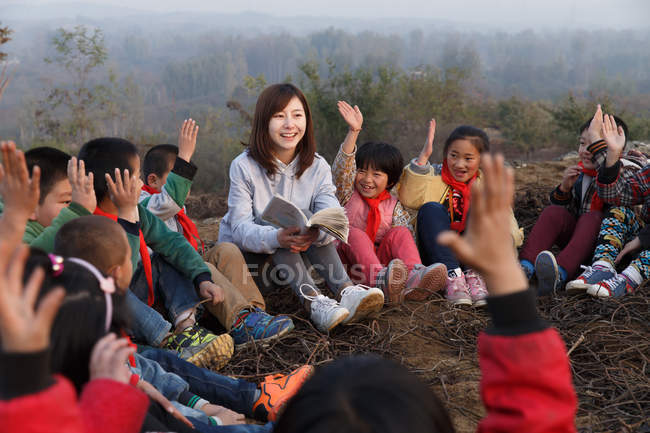 Enseignant rural lisant un livre aux élèves en plein air — Photo de stock
