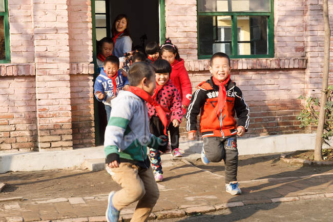Сільський китайський вчитель і учні в школі і на подвір'ї — стокове фото