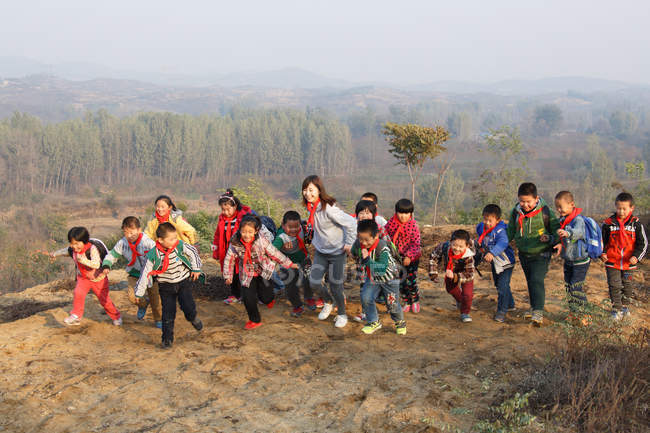 Jóvenes maestras y estudiantes de escuelas chinas jugando en el área rural - foto de stock