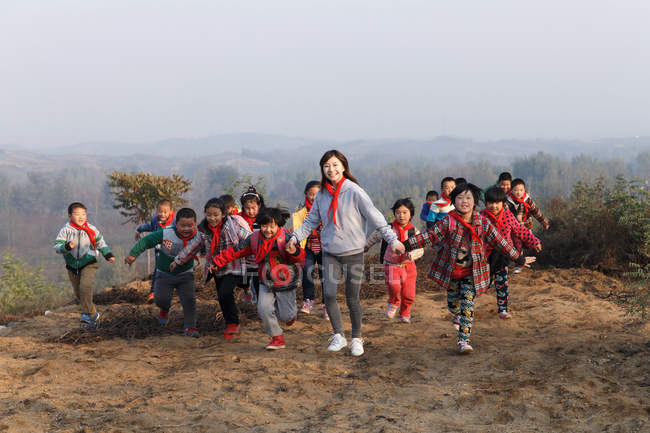 Giovani insegnanti di sesso femminile e studenti della scuola cinese che giocano in zona rurale — Foto stock