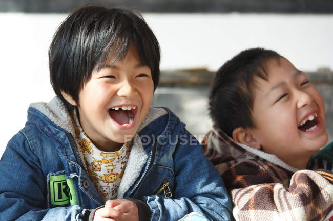 Estudiantes de primaria riendo mientras estudian en la escuela primaria rural - foto de stock