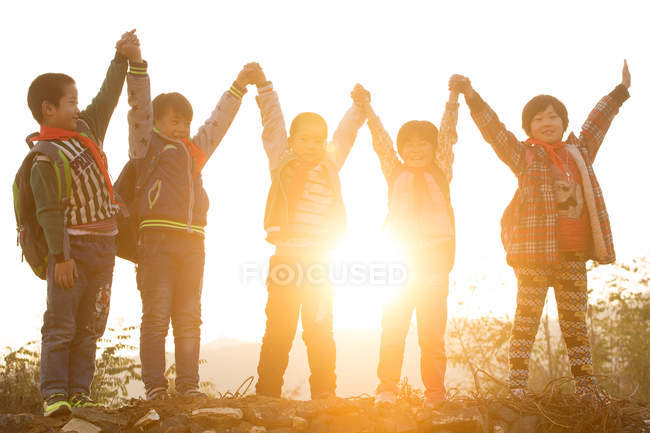Happy rural chinese pupils raising arms and cheering outdoor — Stock Photo