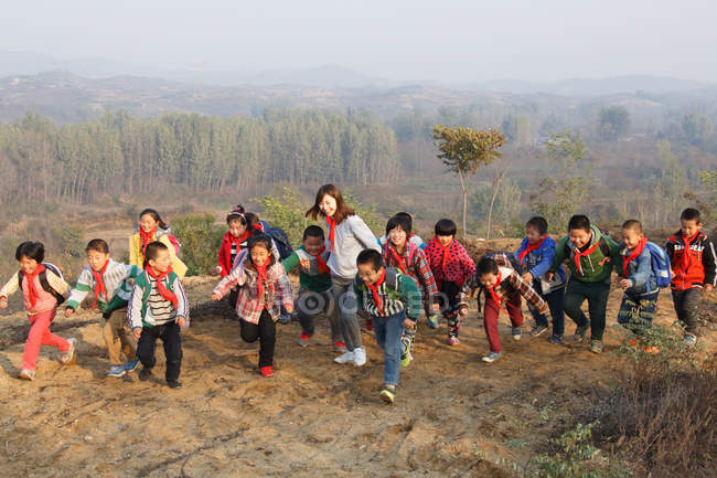 Giovane insegnante femminile e studenti delle scuole rurali cinesi che giocano all'aperto — Foto stock