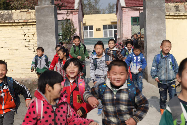 Feliz chino rural pupilos llegar a casa de la escuela - foto de stock