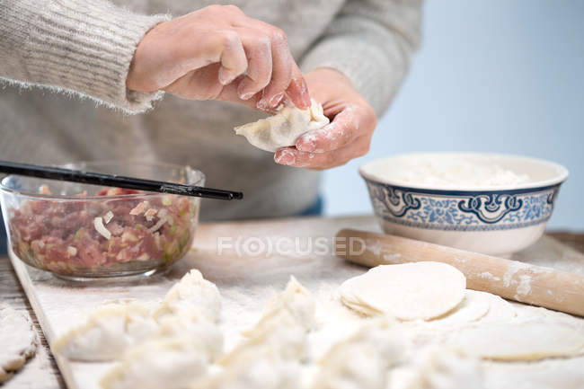 Tiro cortado de mulher com pauzinhos preparando deliciosos bolinhos chineses tradicionais — Fotografia de Stock
