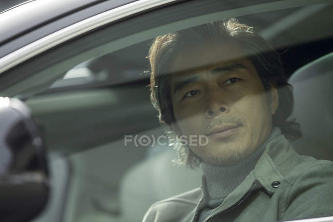 Vista através de janela de vidro de homem chinês maduro sentado no carro — Fotografia de Stock