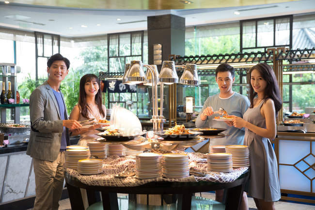 Fröhliche junge Asiaten, die am Buffet stehen und in die Kamera lächeln — Stockfoto
