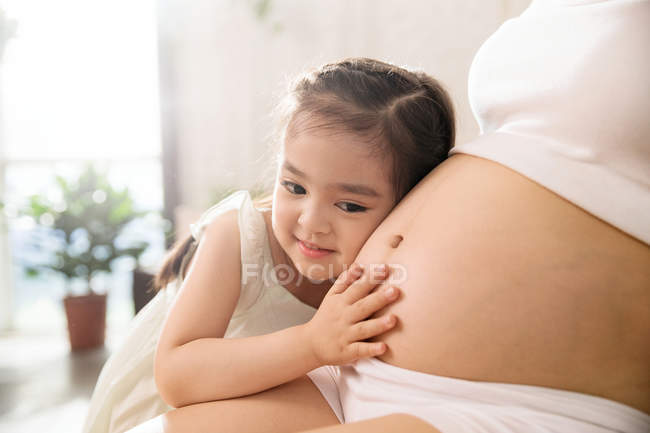 Schnappschuss von süßem kleinen Kind, das Schwangerschaftsbauch hört — Stockfoto