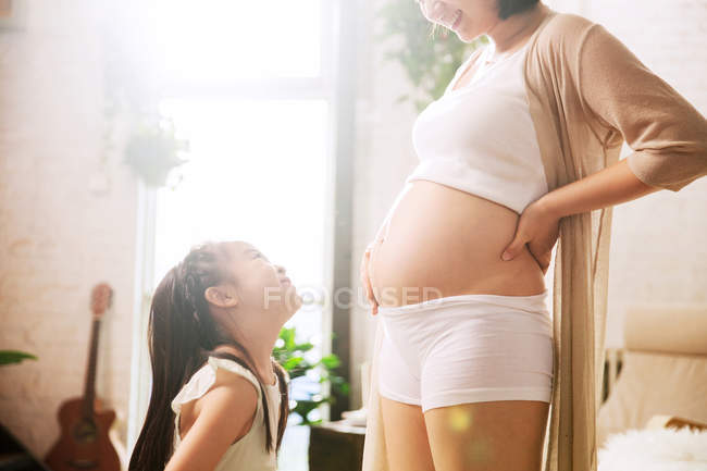 Tiro cortado de criança adorável olhando para a mãe grávida — Fotografia de Stock