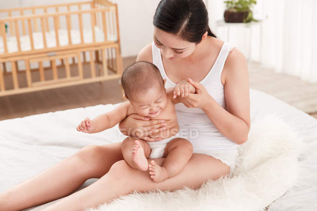 Visão de alto ângulo de feliz jovem mãe brincando com bebê adorável em fralda em casa — Fotografia de Stock