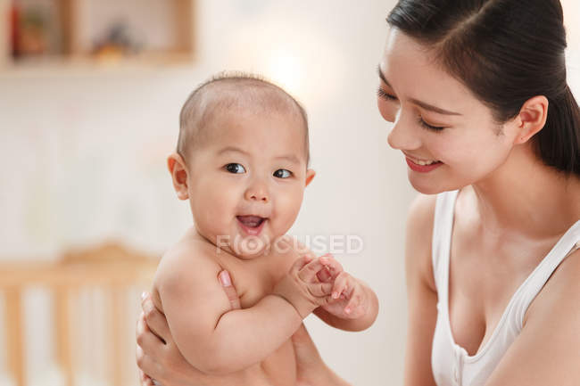 Усміхнена молода мати носить чарівну дитину сміється — стокове фото