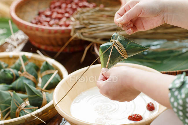 Plan recadré de femme préparant le plat de riz chinois traditionnel zongzi — Photo de stock