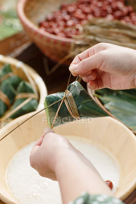 Primer plano vista parcial de la mujer haciendo tradicional plato chino zongzi - foto de stock