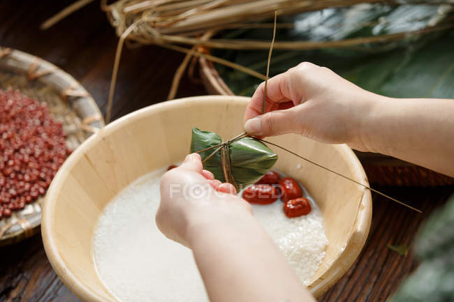 Partial view of middle-aged woman making traditional chinese dish zongzi — Stock Photo