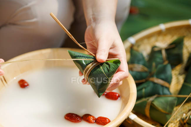 Teilansicht einer Frau mittleren Alters, die traditionelles chinesisches Gericht Zongzi zubereitet — Stockfoto