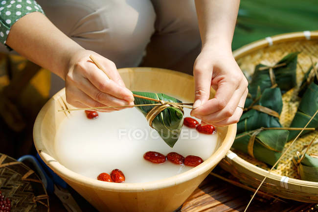 Tiro recortado de mujer de mediana edad haciendo zongzi - foto de stock