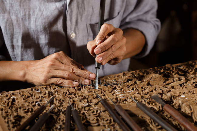 Primo piano vista parziale dell'uomo asiatico durante la lavorazione del legno incisione in officina — Foto stock