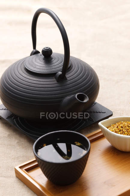 Black ceramic teapot and cup of tea on wooden tray — Stock Photo