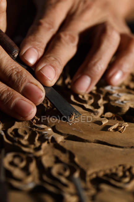 Close-up partial view of asian man during woodworking engraving at workshop — Stock Photo