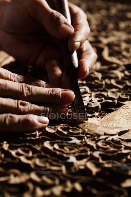 Vista parcial de las manos masculinas durante el grabado en madera en el taller - foto de stock
