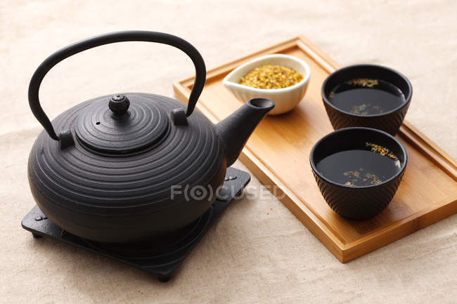 Високий кут зору чорного керамічного чайника і чашок чаю на дерев'яному лотку — стокове фото