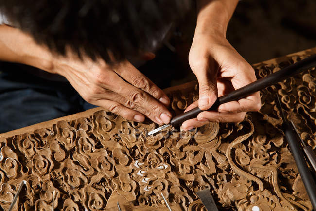 Close-up partial view of asian man during woodworking engraving at workshop — Stock Photo