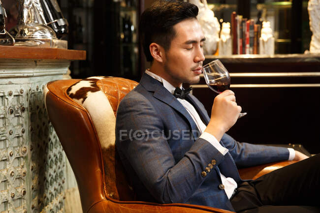 Un joven con una copa de vino tinto - foto de stock
