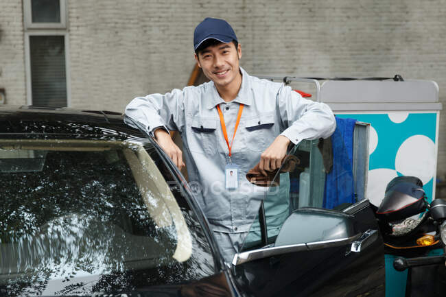 Jeune homme nettoyage voiture — Photo de stock