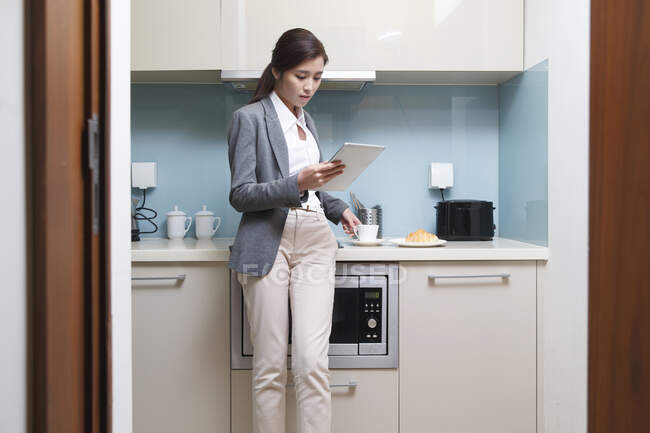 Jovens mulheres usam tablets na cozinha — Fotografia de Stock