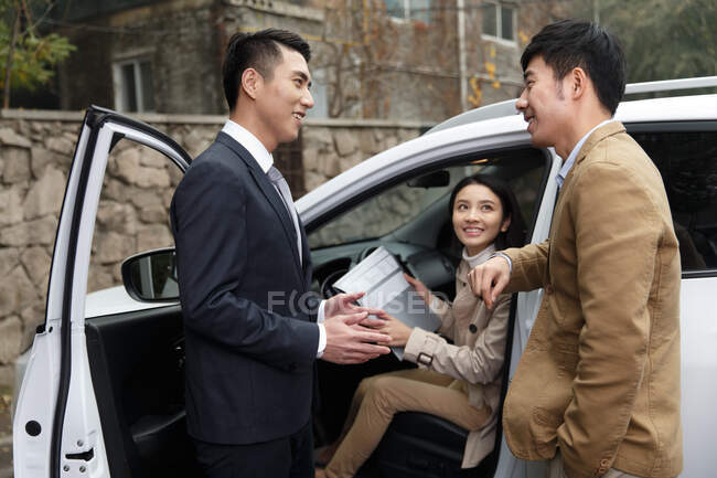 Продавець автомобілів розмовляє з парою — стокове фото