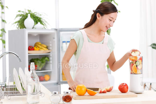 Portrait of young woman cooking in kitchen — Stock Photo