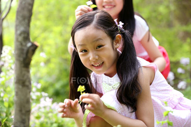 Two girls picking flower in field — Stock Photo