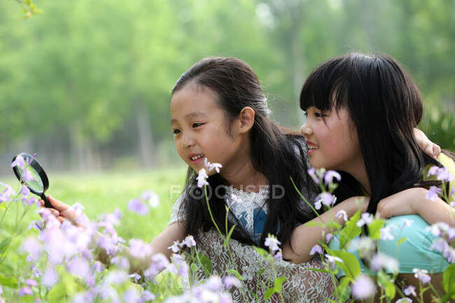 Two girls with magnifying glass — Stock Photo