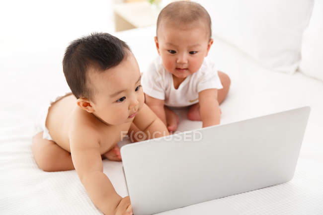 Дві чарівні азіатські немовлята використовують ноутбук — стокове фото