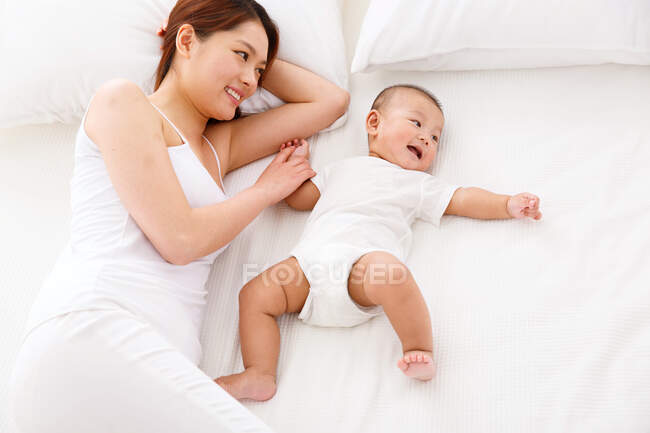 Mom and baby are playing on the bed. — Stock Photo