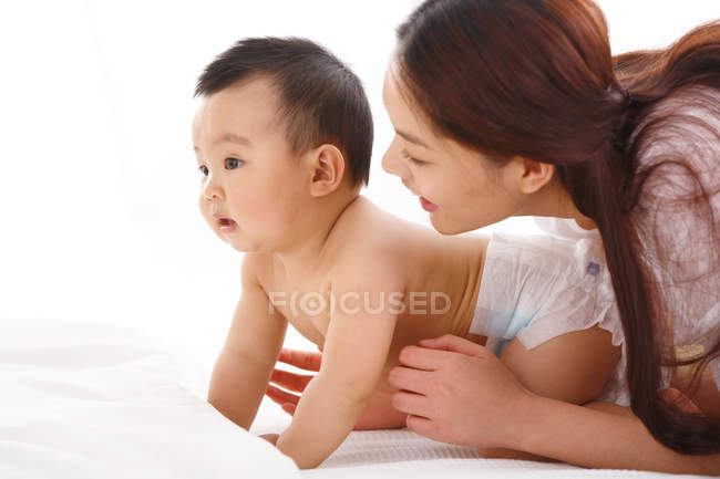 Feliz jovem mãe olhando para o bebê bonito em casa — Fotografia de Stock