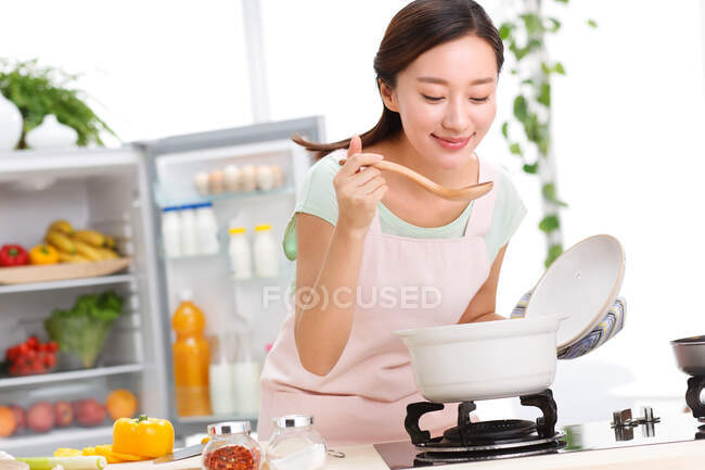 Porträt einer jungen Frau, die in der Küche kocht — Stockfoto