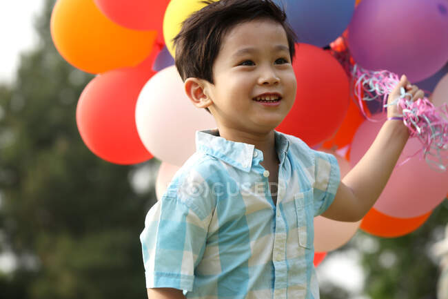 Garçon tenant tas de ballons — Photo de stock