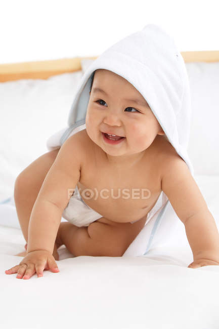 Cute happy asian baby boy in diaper and towel on bed — Stock Photo