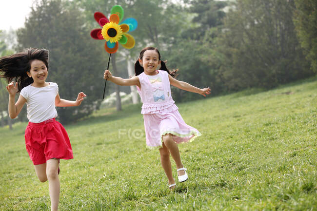 Deux filles jouent avec un moulin à vent en papier — Photo de stock