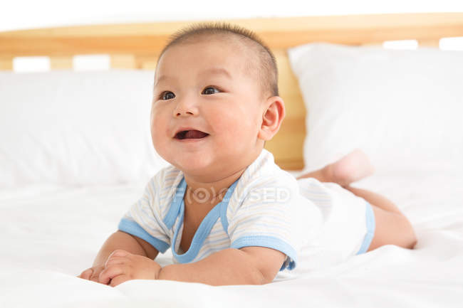 Nahaufnahme des entzückenden glücklichen chinesischen Jungen, der auf dem Bett liegt — Stockfoto