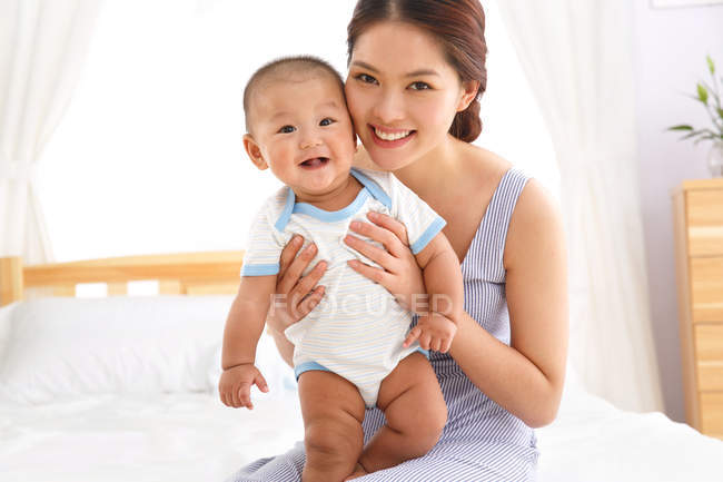 Щаслива молода мати з милою дитиною посміхається на камеру — стокове фото