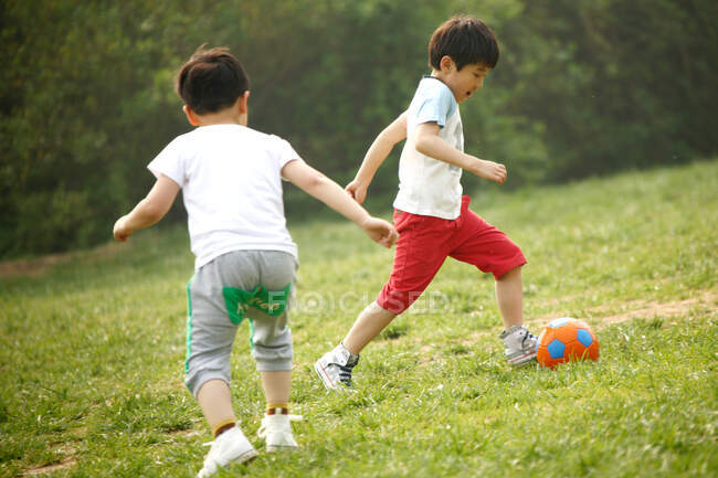 Dos chicos jugando al fútbol en el campo - foto de stock